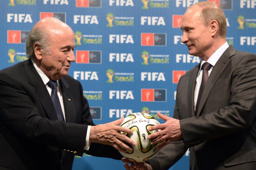 FIFA President Sepp Blatter, left, passes a soccer ball to Russian President Vladimir Putin in 2014 during the official handover ceremony of the 2018 World Cup to Russia.