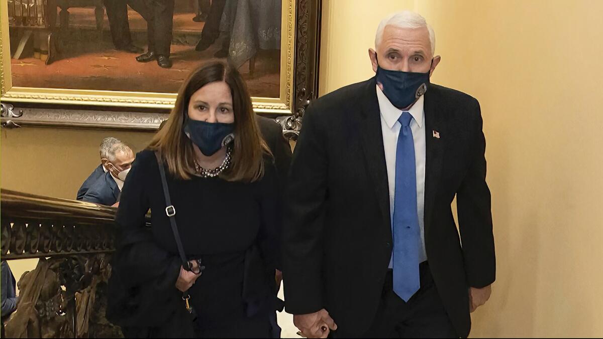 Vice President Mike Pence and his wife, Karen, in face masks walk at the Capitol.