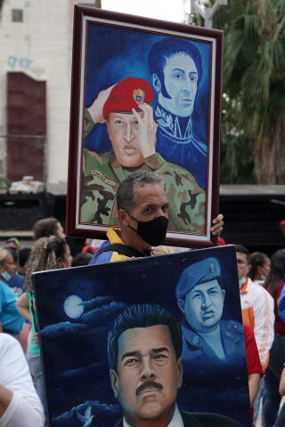 People hold paintings of Hugo Chavez during a rally.