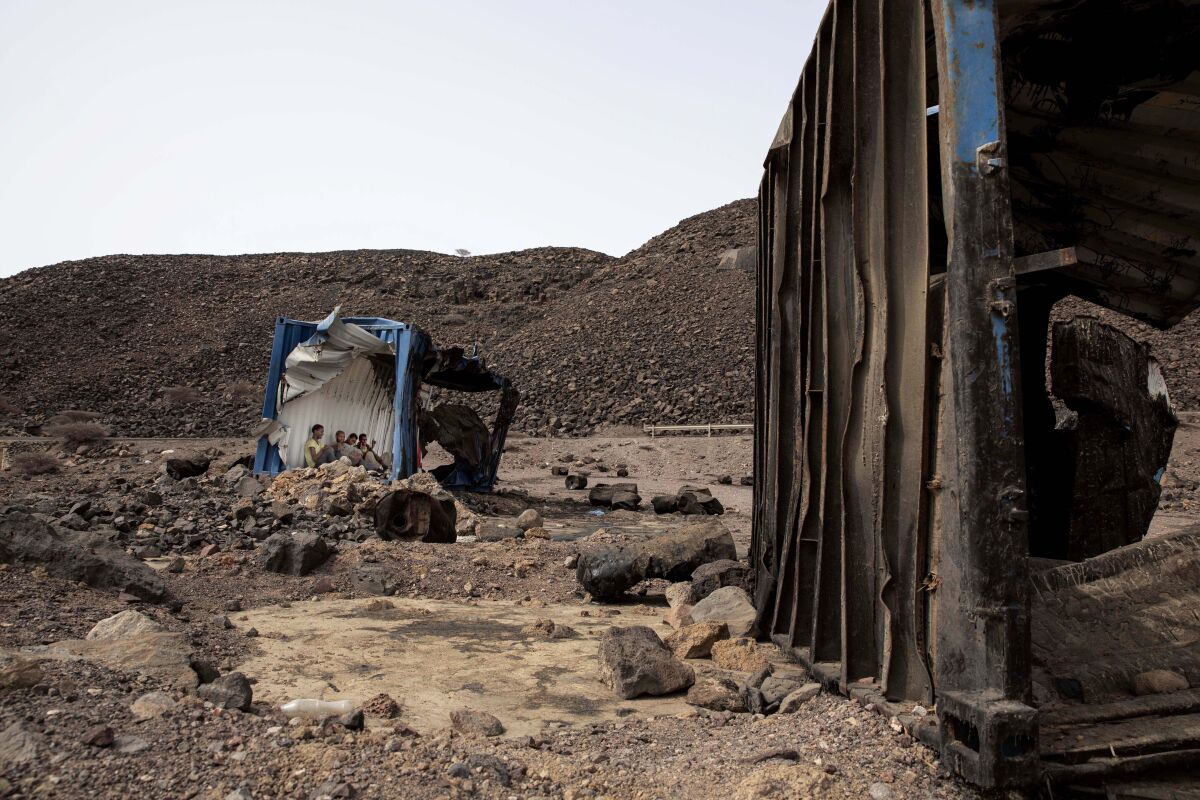 In this July 14, 2019 photo, 35-year-old Mohammed Eissa, an Ethiopian farmer and other migrants he met along the way, take shelter inside a damaged shipping container on the side of a highway, near Lac Assal, Djibouti. Over the past three years, the IOM reported 9,000 Ethiopians were deported each month. Many migrants have made the journey multiple times in what has become an unending loop of arrivals and deportations. Eissa is among them. This is his third trip to Saudi Arabia. (AP Photo/Nariman El-Mofty)