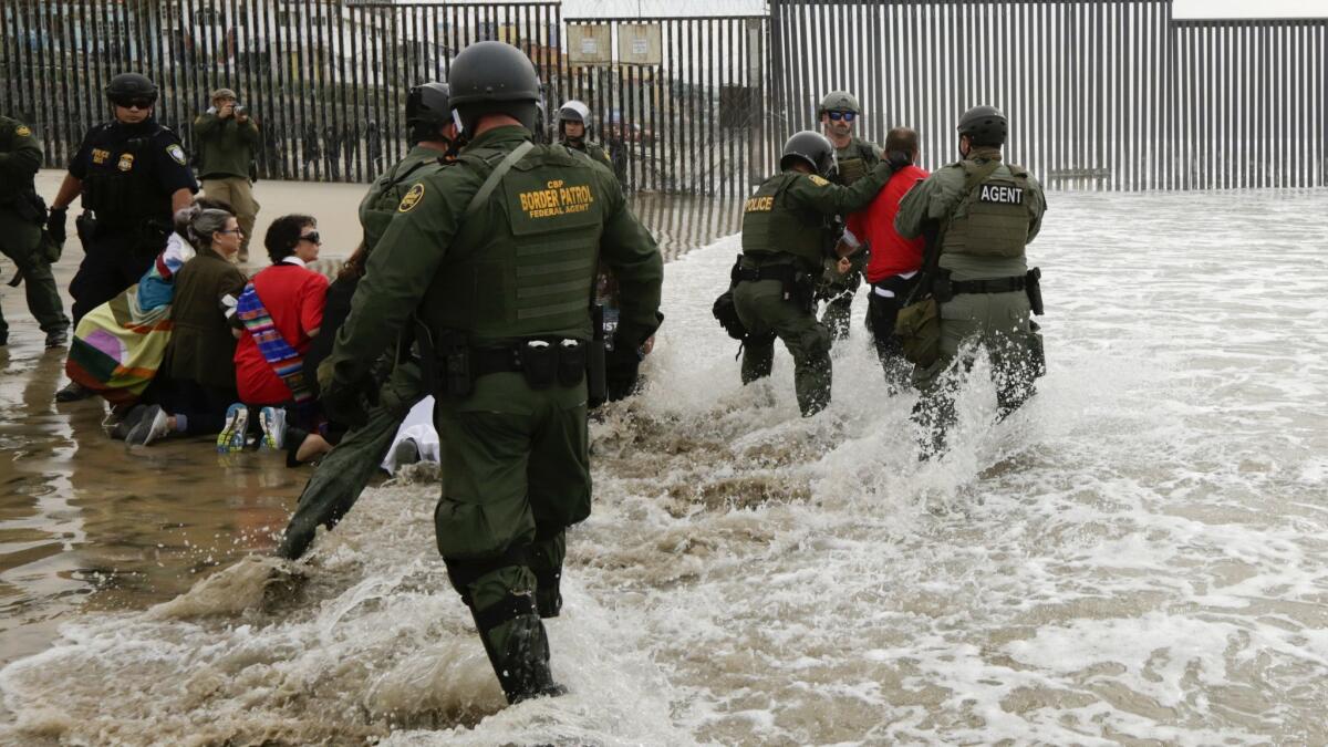 Border Patrol officers detain a man during a protest near the border with Tijuana on Monday.