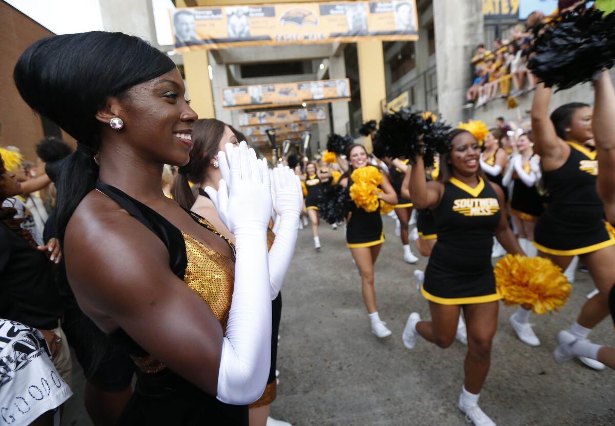 FILE-In this Sept. 5, 2015 file photo, Southern Mississippi Dixie Darlings clap as cheerleaders run past prior to an NCAA college football game against Mississippi State at M.M. Roberts Stadium in Hattiesburg, Miss. The University of Southern Mississippi announced that it is considering renaming its dance team, the "Dixie Darlings." The marching band has announced that it will select a new name to replace the nickname they've had since 1954. (AP Photo/Rogelio V. Solis)