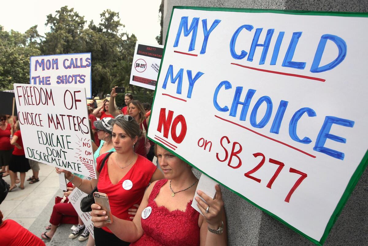 Karman Willmer, left, and Shelby Messenger rally against SB 277, a California measure requiring schoolchildren to get vaccinated, outside the Capitol in Sacramento, Calif.