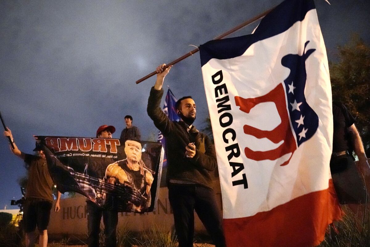 A supporter of Joe Biden waves a flag in front of the Clark County Election Department in Las Vegas.
