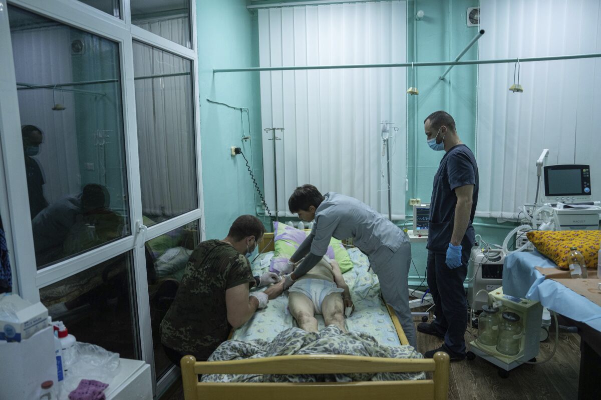 Médicos tratan a una anciana en el departamento de cuidados intensivos del hospital de Zolochiv, región de Járkiv, Ucrania, el domingo 31 de julio de 2022. (Foto AP/Evgeniy Maloletka)