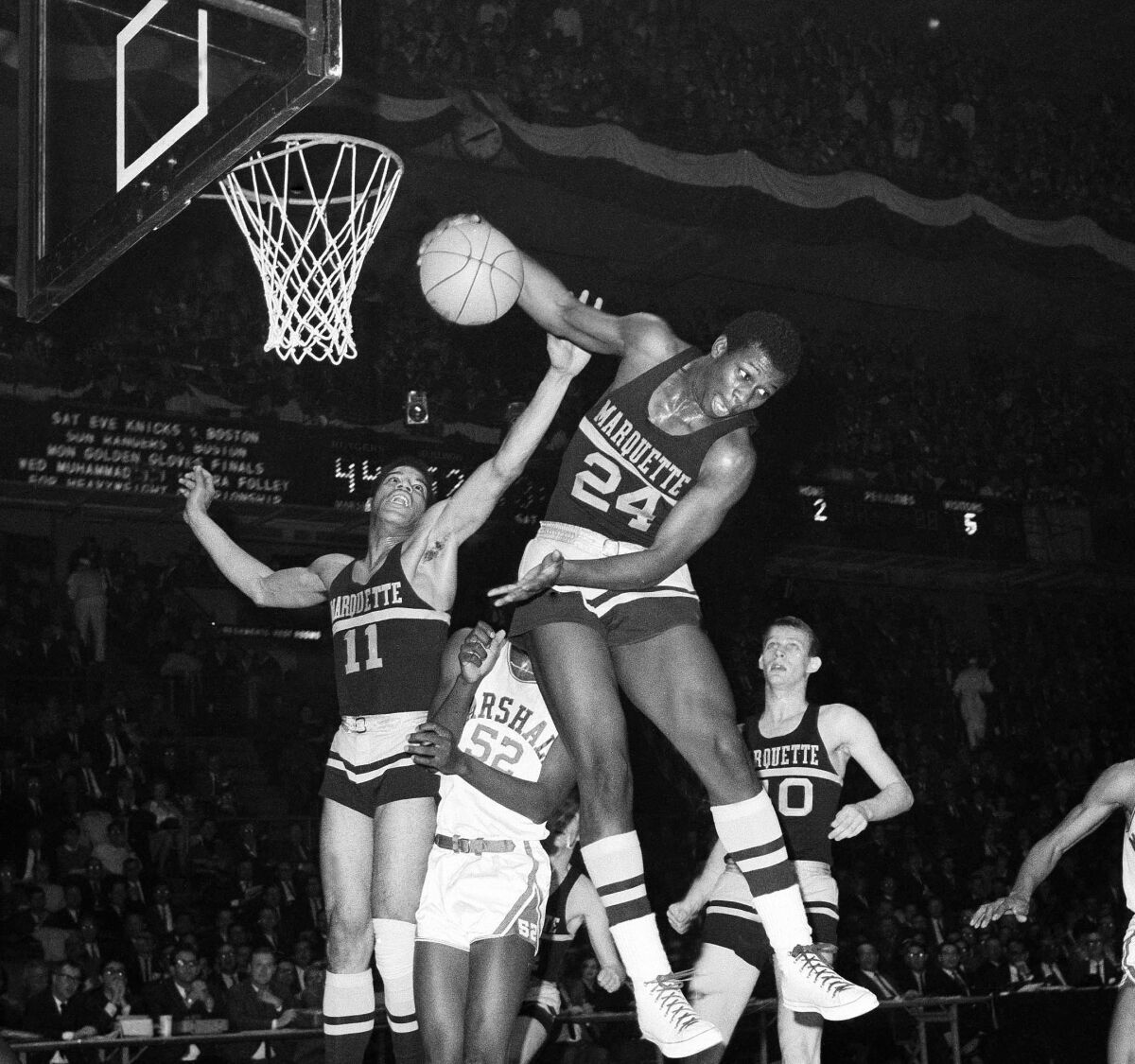 FILE - Teammates George Thompson (24) and Pat Smith (11) of Marquette leap for rebound in the first half of a college basketball against Marshall University at Madison Square Garden in New York, March 16, 1967. Thompson, who played for Marquette from 1967-69 and remains one of the program’s all-time leading scorers, has died. He was 74. Marquette announced Thompson died Wednesday, June 8, 2022 at his Milwaukee home due to complications from diabetes. (AP Photo)
