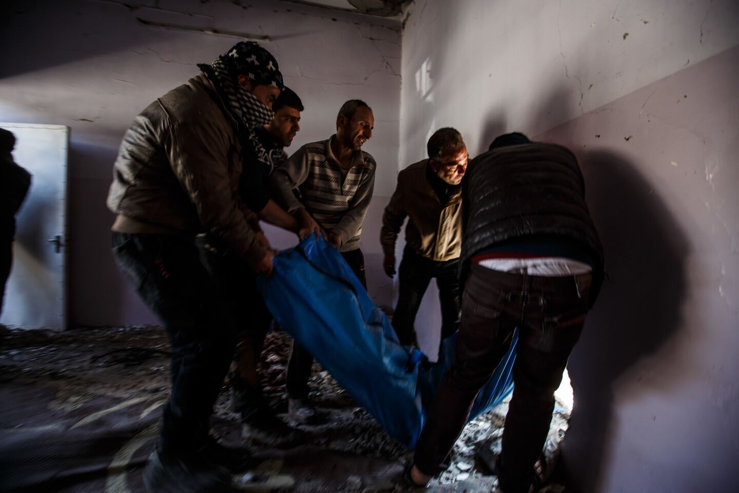 Iraqi residents carry out body bags after recovering corpses from the rubble inside a house destroyed by an airstrike in Mosul.