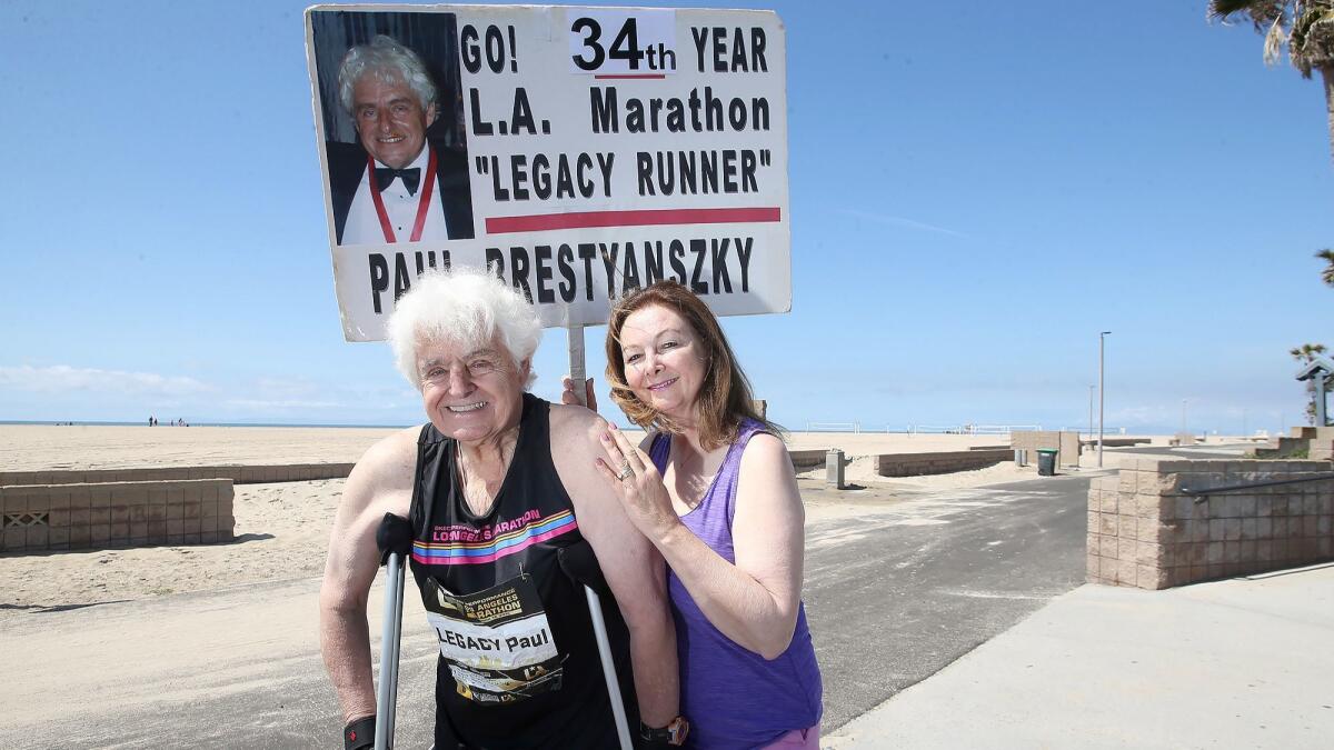 Mila Cangelosi-Brestyanszky holds a sign she made for her husband, Paul Brestyanszky, who has run the Los Angeles Marathon all of its 33 years.