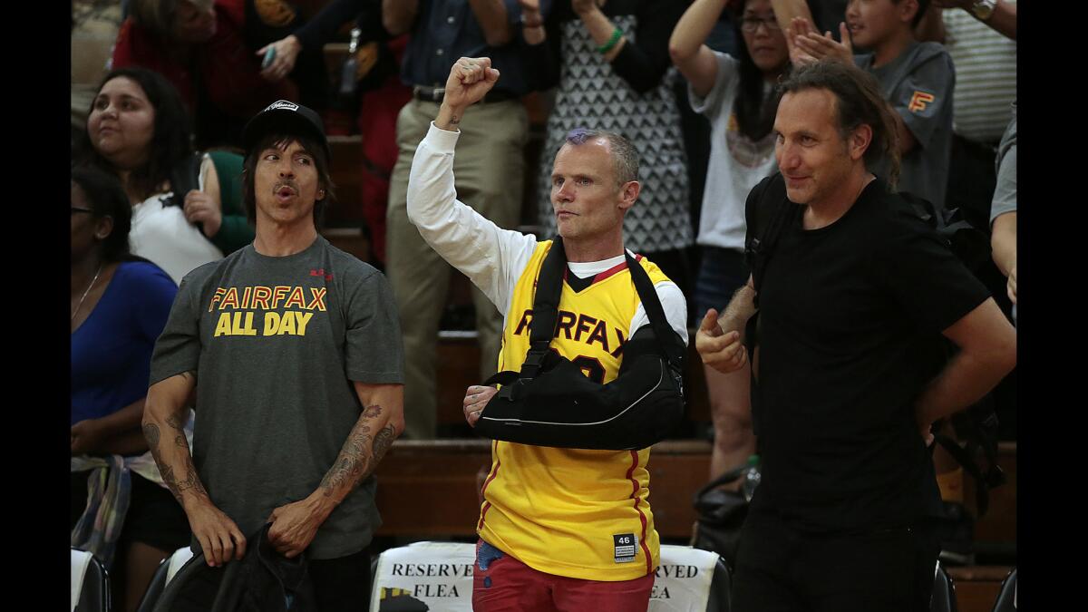 Red Hot Chili Peppers band mates Anthony Kiedis, left, and Flea, center, cheer along with friend Dave Mushegian as they watch Fairfax defeat Etiwanda, 58-50, in a Southern California Regionals Open Division semifinal at Fairfax High School on Tuesday.