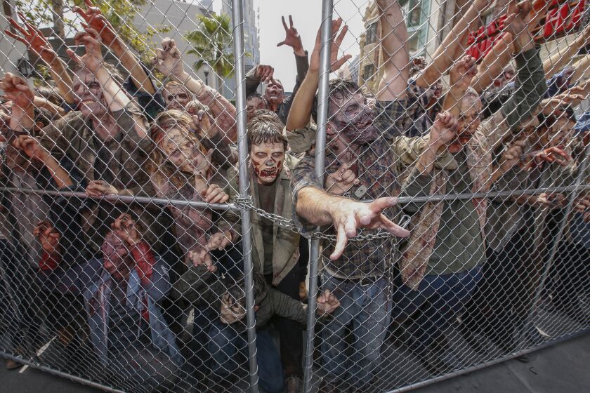 Zombies are held at bay by a chain-link fence during the press preview of the Universal Studios' "Walking Dead' attraction.