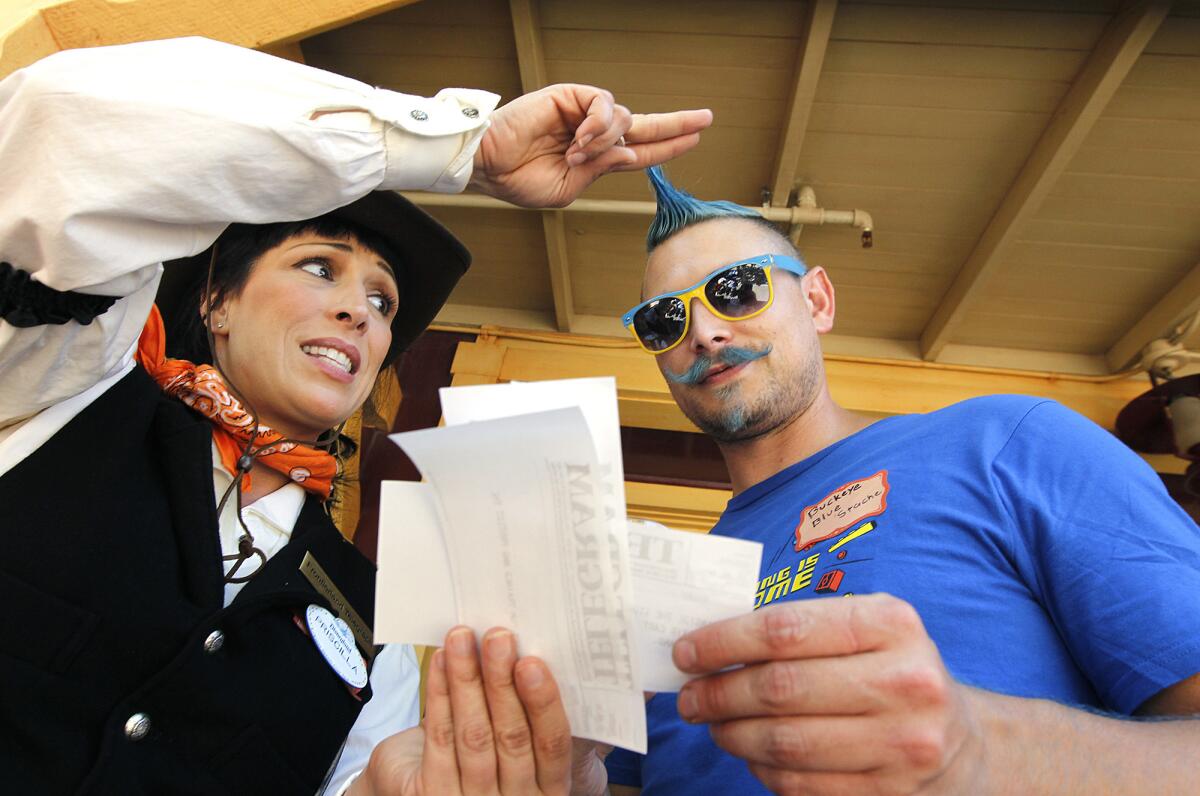 Jennifer Bascom, left, of Disneyland, gives a telegram to Disneyland guest Keith Kocienski of Fullerton, right, while playing a live action role playing game in Frontierland.