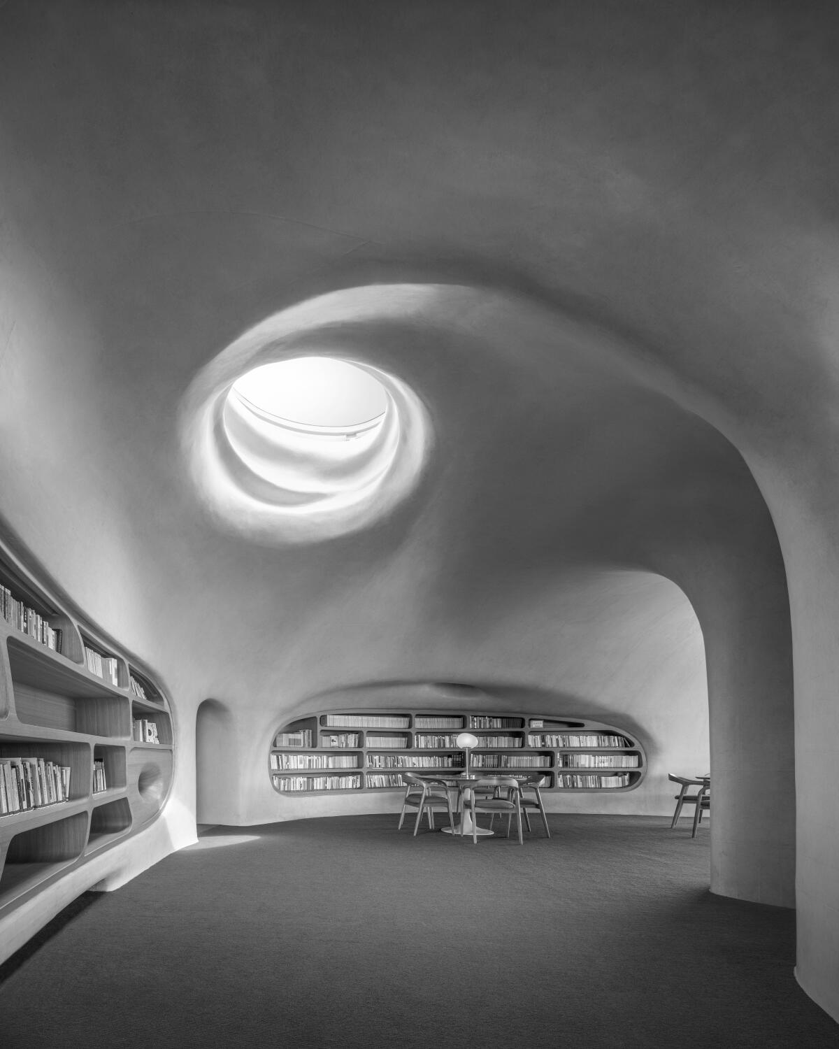 A cavernous interior with whimsical curves and light streaming through a circular opening.