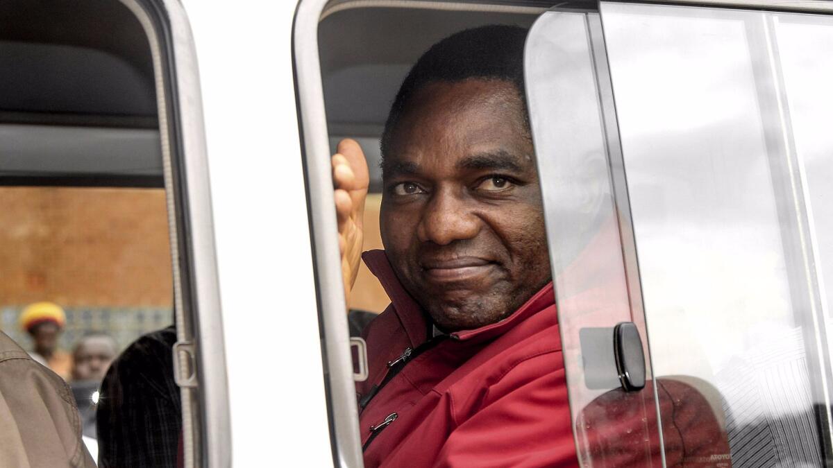 Jailed Zambian opposition leader Hakainde Hichilema, facing treason charges and possibly the death penalty, waves to supporters from a police van as he leaves a court hearing April 18. (Dawood Salim / AFP/Getty Images)