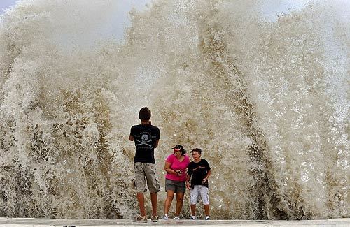 Onlookers pose for pictures as waves generated by Hurricane Ike crash against the sea wall in Galveston, Texas.