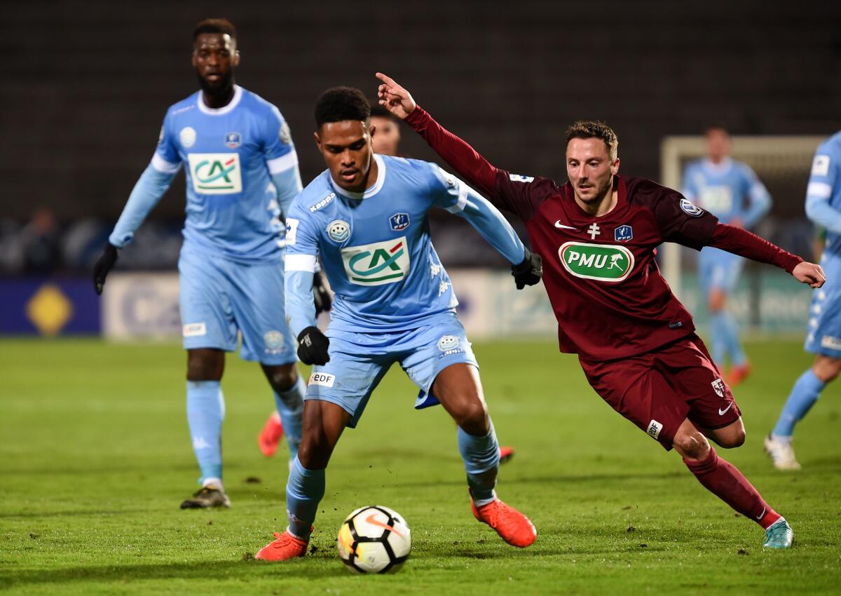 Tours' French midfielder Rayan Raveloson, center, vies for the ball 