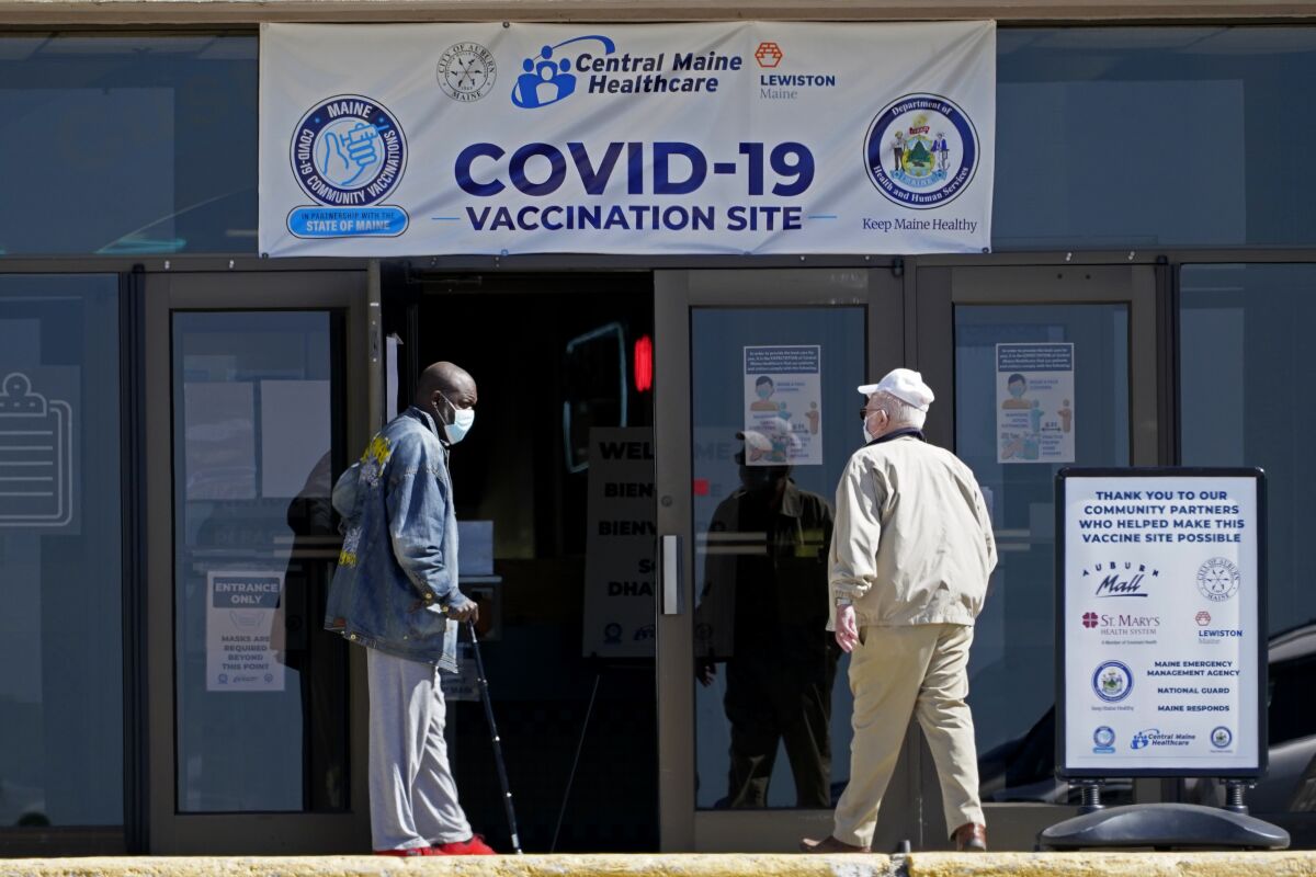 A man holds the door for another as they arrive at a COVID-19 vaccination clinic