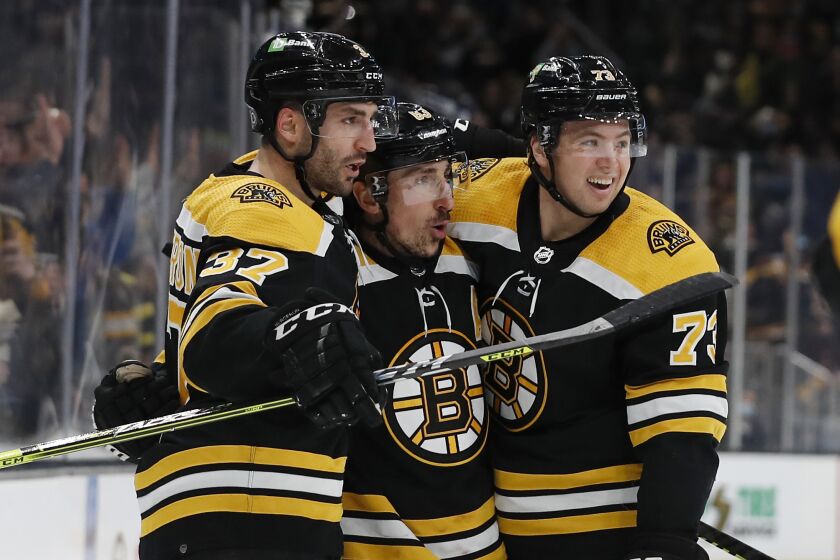 FILE - Boston Bruins' Brad Marchand, center, is congratulated by Patrice Bergeron (37) and Charlie McAvoy after scoring a goal against the Nashville Predators during an NHL hockey game Jan. 15, 2022, in Boston. Marchand, the team’s No. 1 scorer last season, will miss the first six weeks recovering from hip surgery. Bergeron spent most of the summer with one skate out the door but is back for another run at the title. Top defenseman McAvoy will miss about two months while recovering from shoulder surgery. (AP Photo/Winslow Townson, File)