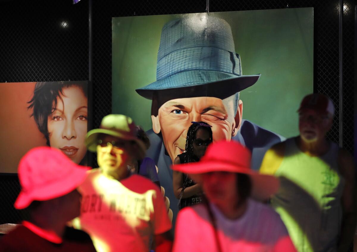 Guests walk by Frank Sinatra's trademark wink in the Art of Music Experience at the Orange County Fair on Thursday.