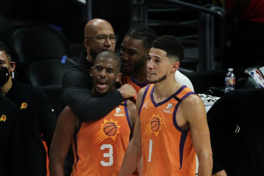 Suns Coach Monty Williams hugs guard Chris Paul as teammates Jae Crowder and Devin Booker (1) watch final seconds of a win.