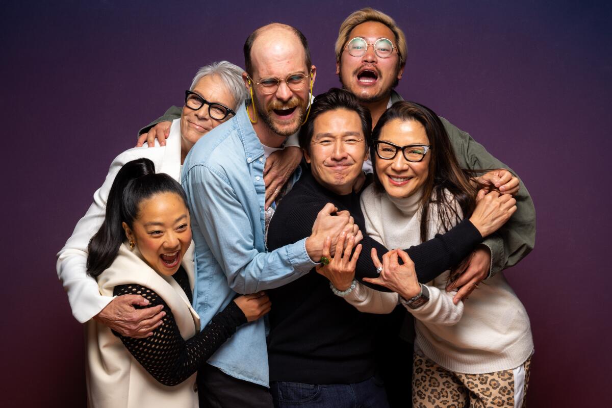 Four cast members and the two writer-directors of "Everything Everywhere All at Once" laugh in a group hug for a portrait.