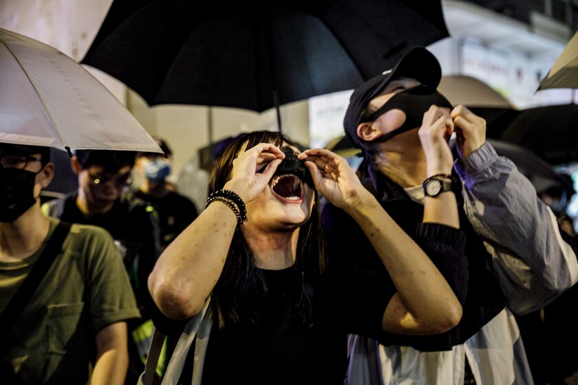 Protesters adjust their face masks to chant during a rally Sept. 2 in Hong Kong. At least a dozen mainlanders have been held or threatened by Chinese authorities after having participated in the Hong Kong demonstrations.
