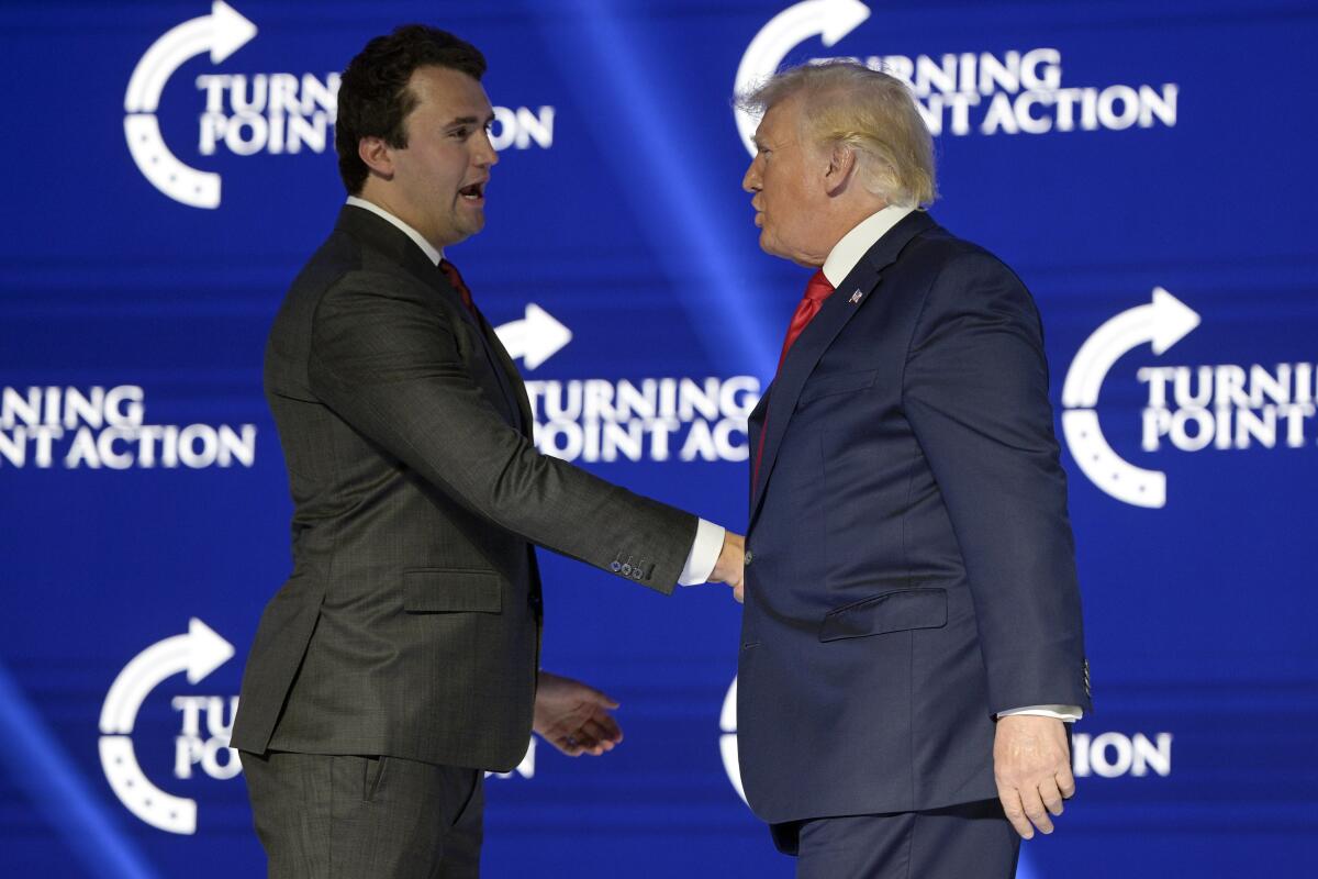 Charlie Kirk and Donald Trump shake hands.