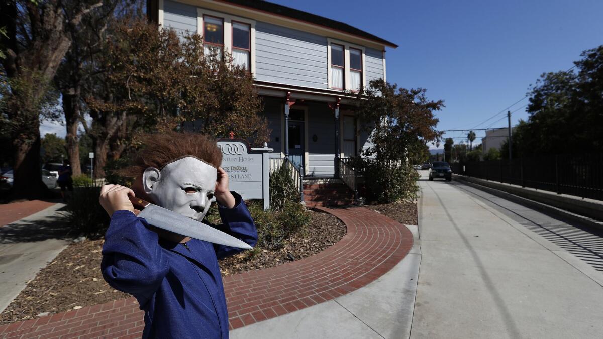 Ben Brown, 10, of Sedona, Ariz., is dressed as the villain, Michael Myers from the 1978 horror classic "Halloween" while visiting the "Myers house," background, on Meridian Avenue in South Pasadena, where much of the movie was filmed.