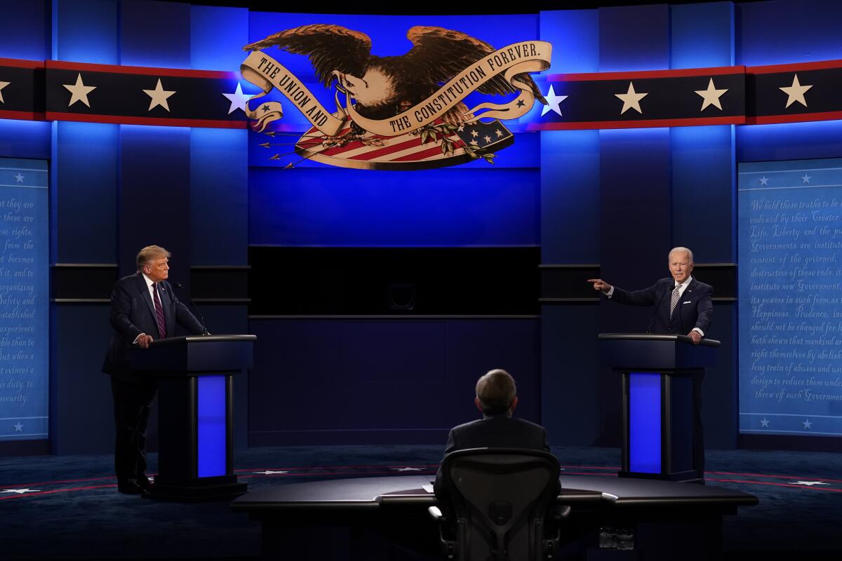 President Trump and former Vice President Joe Biden stand behind podiums on the debate stage. 