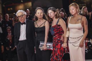 Woody Allen in a tuxedo poses next to wife Soon-Yi Previn in black dress and Manzie Tio Allen, Bechet Allen in dresses