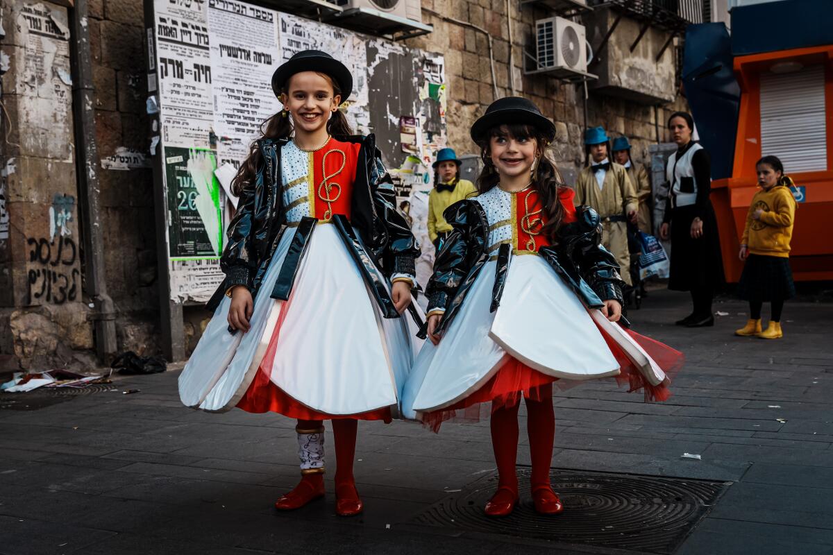 Leah Oritz, 8, left, and Sari Oritz, 5, pose for photographs at Purim festivities.