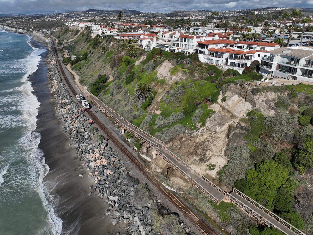 An aerial view of coastal train tracks partly covered by landslide debris.