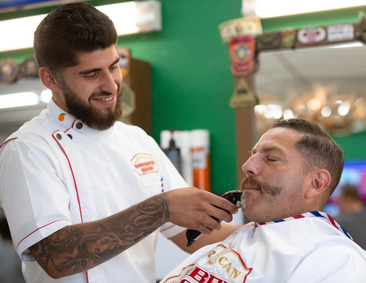 Edward Mugica shaves off Sean Chavarria's beard at American Barbershop in Orange on Thursday.