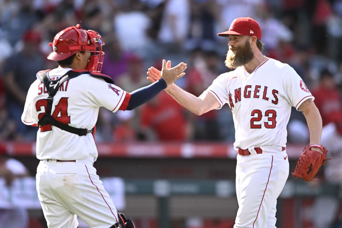 Angels pitcher Archie Bradley and catcher Kurt Suzuki reach out hands to each other.