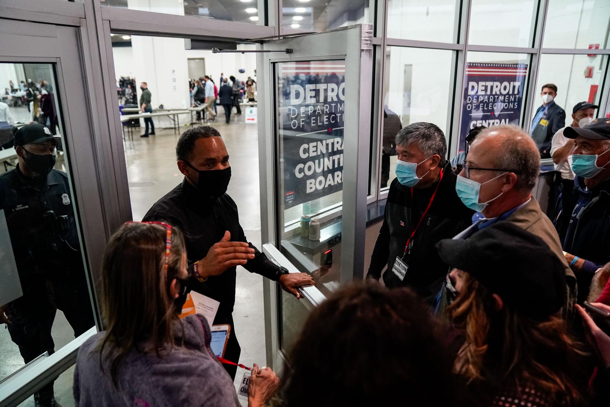 An election worker talks to people at an entrance.