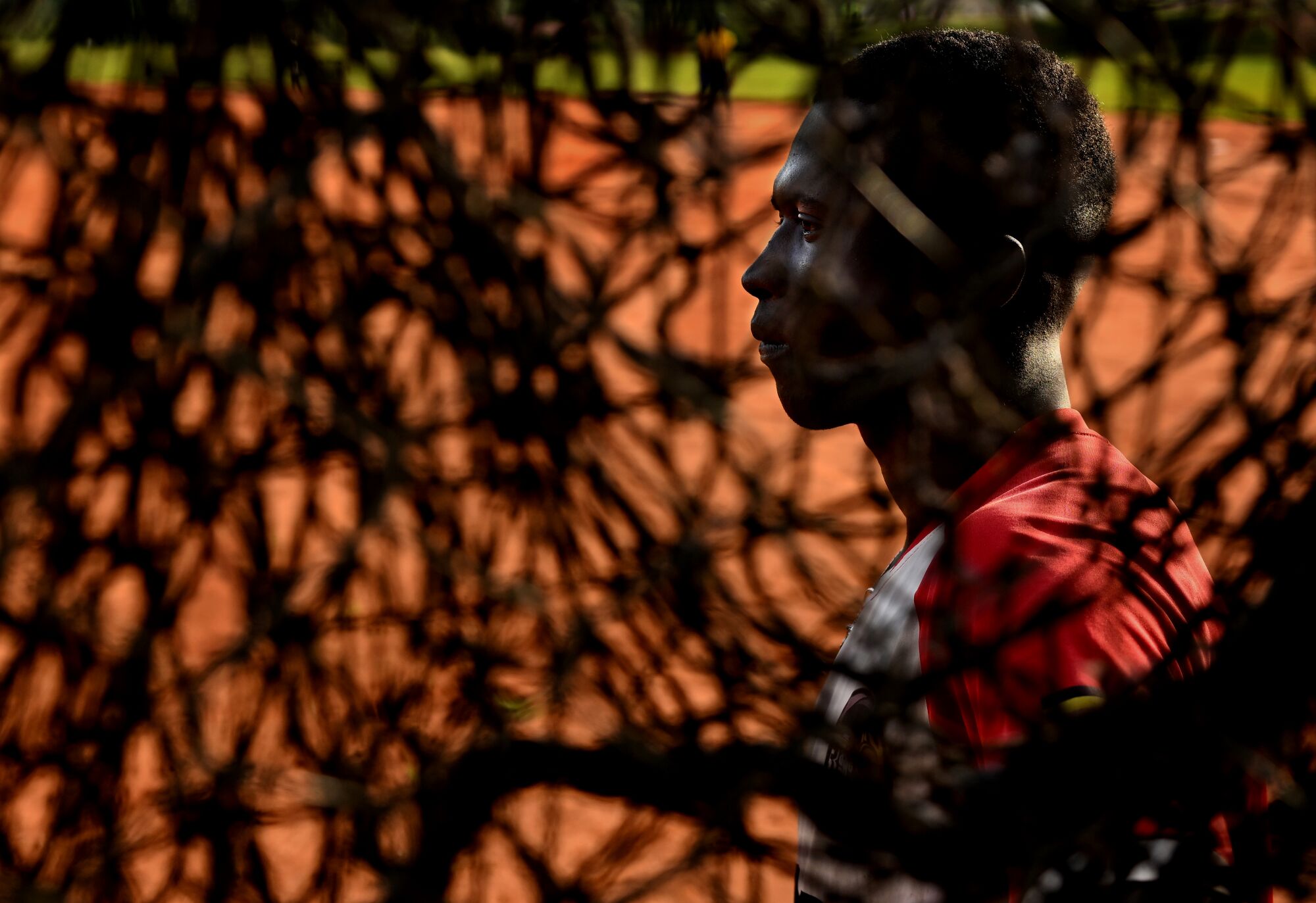 A young man is framed behind silhouetted netting.