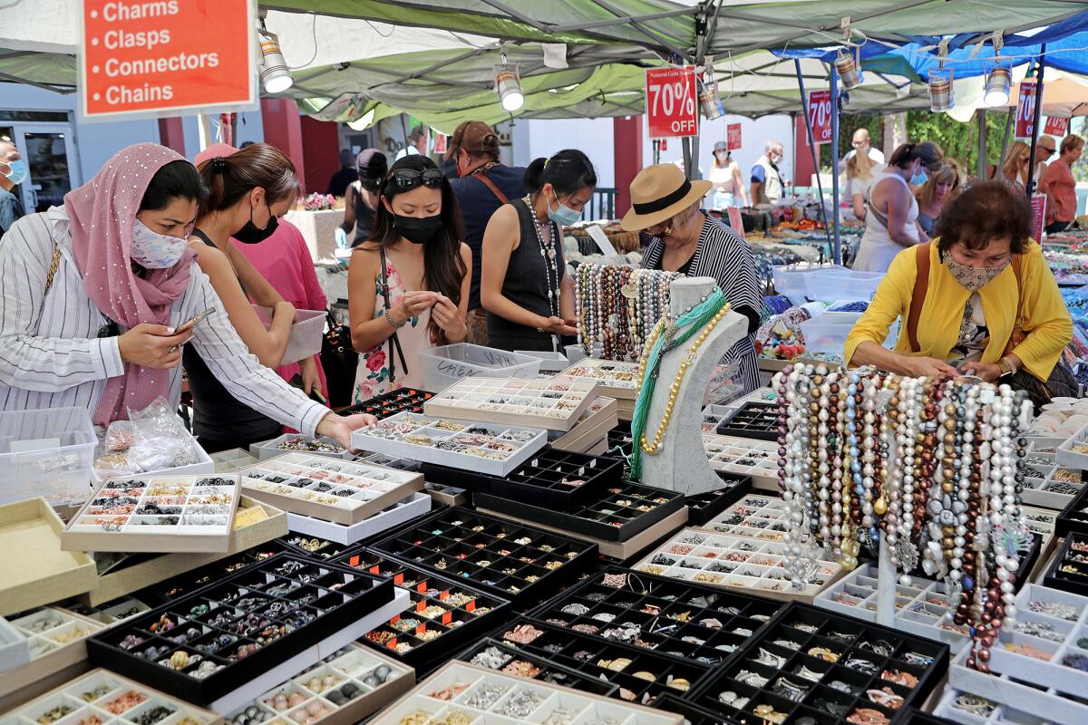 Shoppers search through jewelry by Jennifer Gems Bead & Design during GemFaire on Friday at the OC Fair & Event Center.