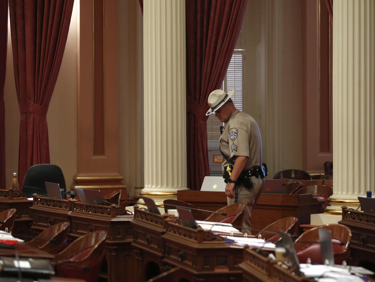 A CHP officer inspects desks in the California Senate chamber