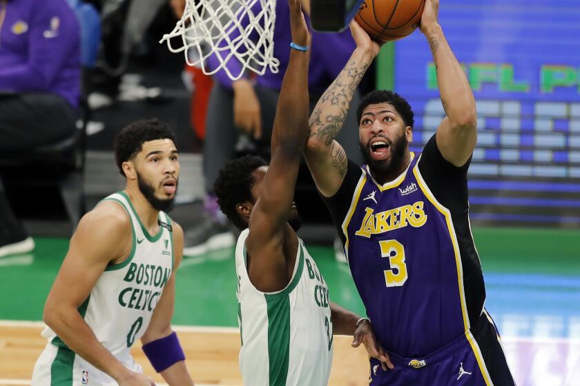 Los Angeles Lakers' Anthony Davis (3) shoots against Boston Celtics' Semi Ojeleye (37) and Jayson Tatum (0) during the first half of an NBA basketball game Saturday, Jan. 30, 2021, in Boston. (AP Photo/Michael Dwyer)