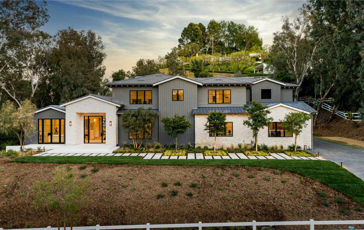 Large windows and a glass entryway are seen in an exterior view of the modern farmhouse-style home.