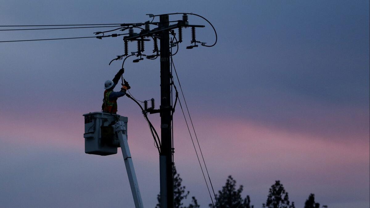 In this Nov. 26, 2018, file photo, a Pacific Gas & Electric lineman works to repair a power line in fire-ravaged Paradise, Calif.