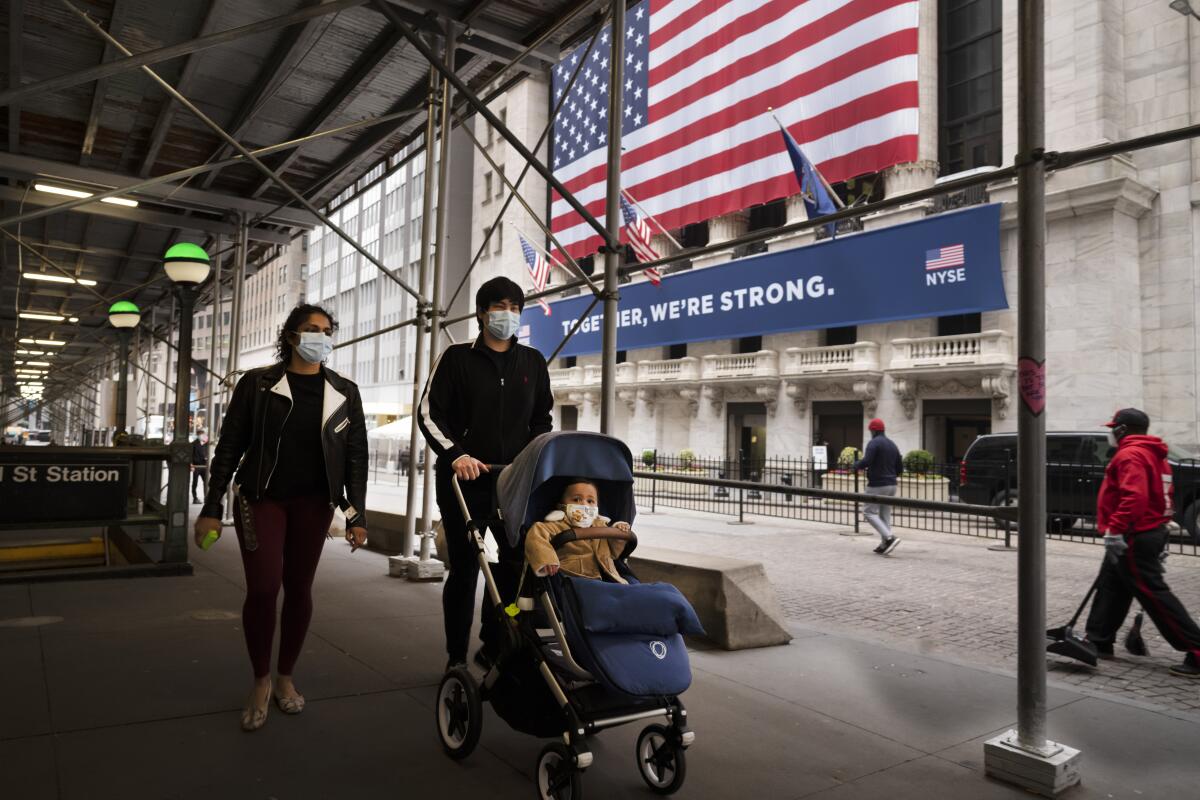 A family wearing masks passes the New York Stock Exchange on May 26. 