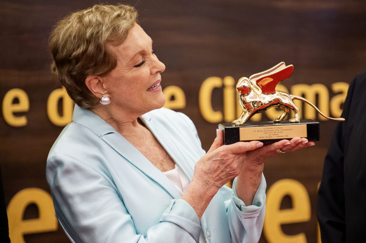 A woman holds up a statuette 