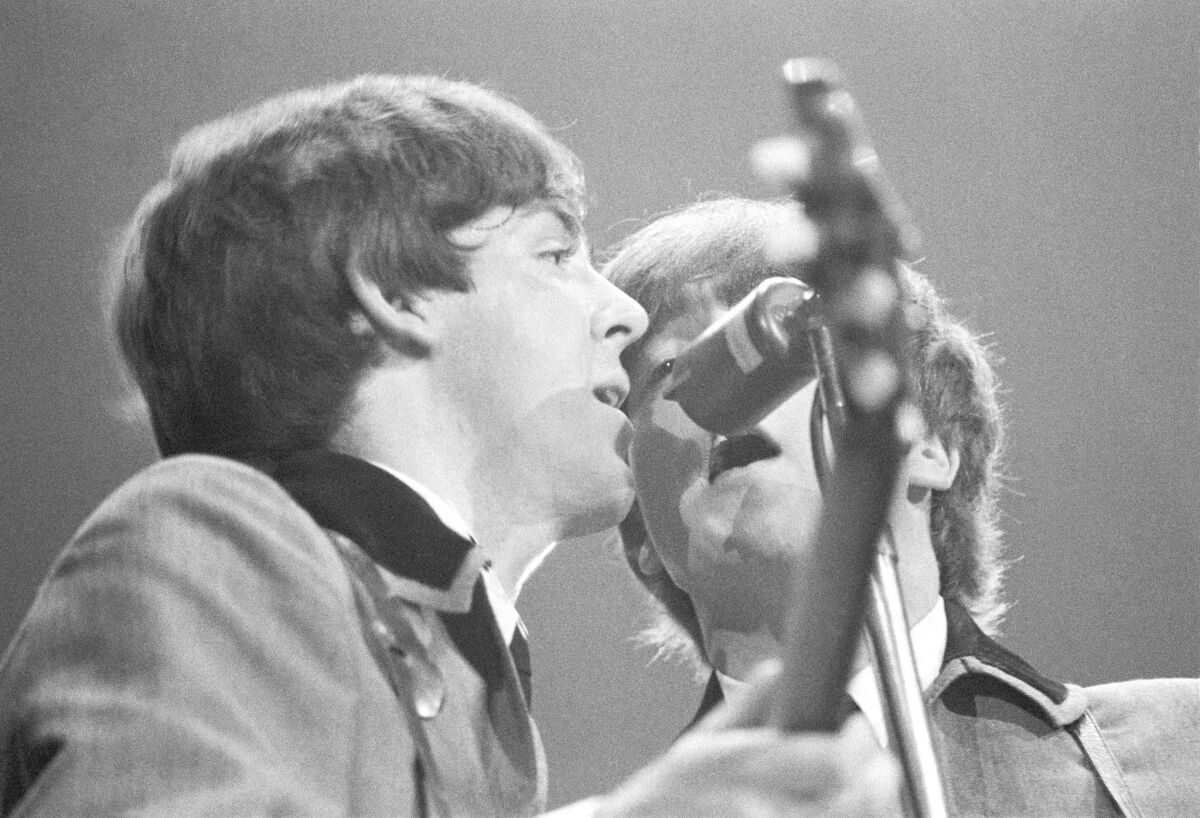 Paul McCartney, left, and John Lennon share a microphone at the Washington Coliseum on Feb. 11, 1964.
