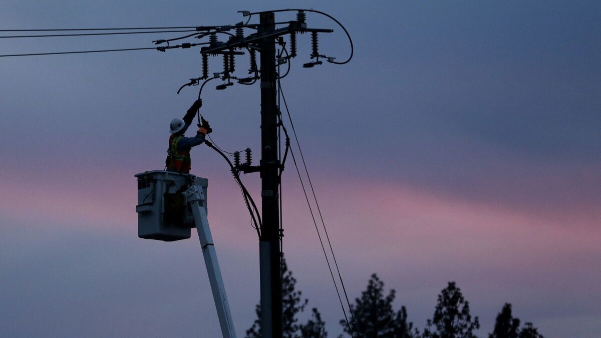A Pacific Gas & Electric lineman works to repair a power line in fire-ravaged Paradise, California