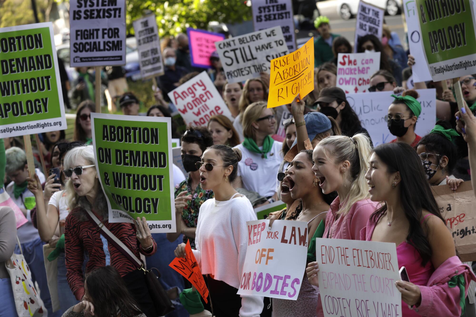 People hold signs in support of abortion rights and expansion of the Supreme Court