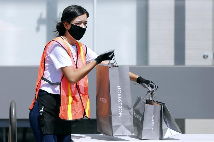 Nordstrom employee Krista Islas brings out bags with items ordered by customers at South Coast Plaza.