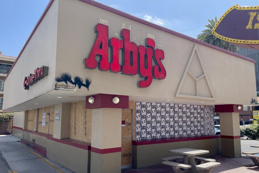A photo outside Arby's Hollywood boarded with plywood and wheatpaste art.