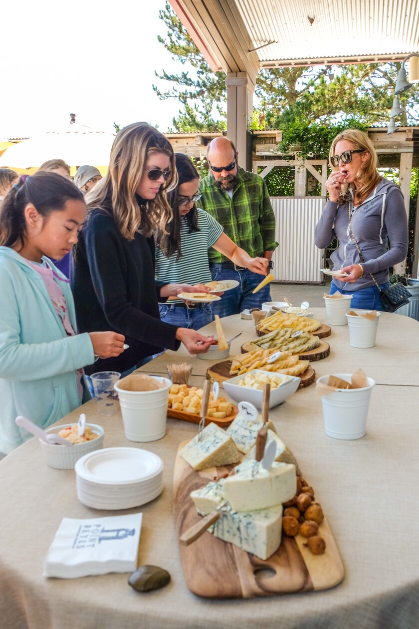 People gather around a table as they taste cheese