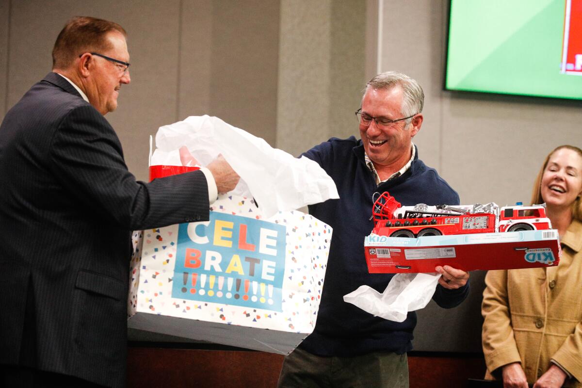 Santee Mayor John Minto watches as former fire chief John Garlow receives a toy fire engine in honor of his retirement.