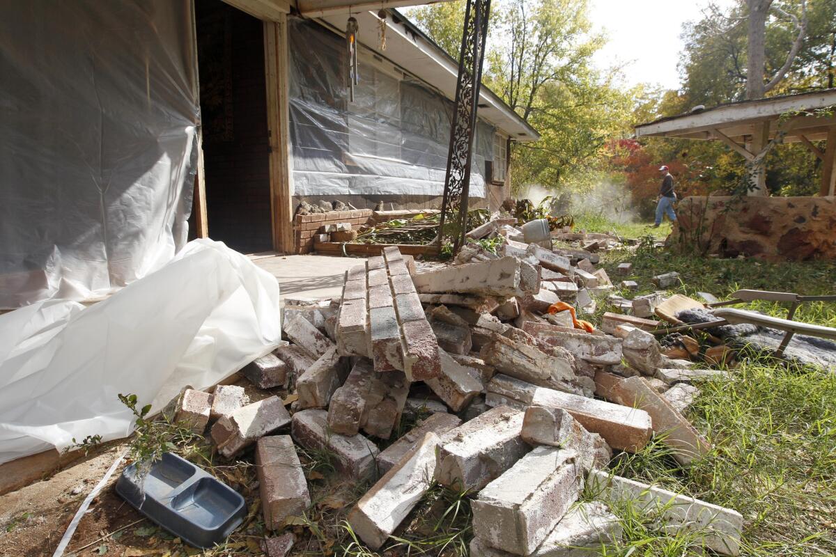 In this 2011 file photo, Chad Devereaux works to clear up bricks that fell from his in-laws' home in Sparks, Okla., after two earthquakes hit the area in less than 24 hours. A government report released Thursday tied seismic activity to fracking used in oil and gas drilling.